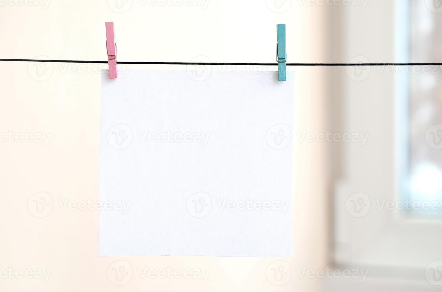 White blank cards on rope, light wall background. Creative reminder, small sheets of paper on old clothespin, memo backdrop photo