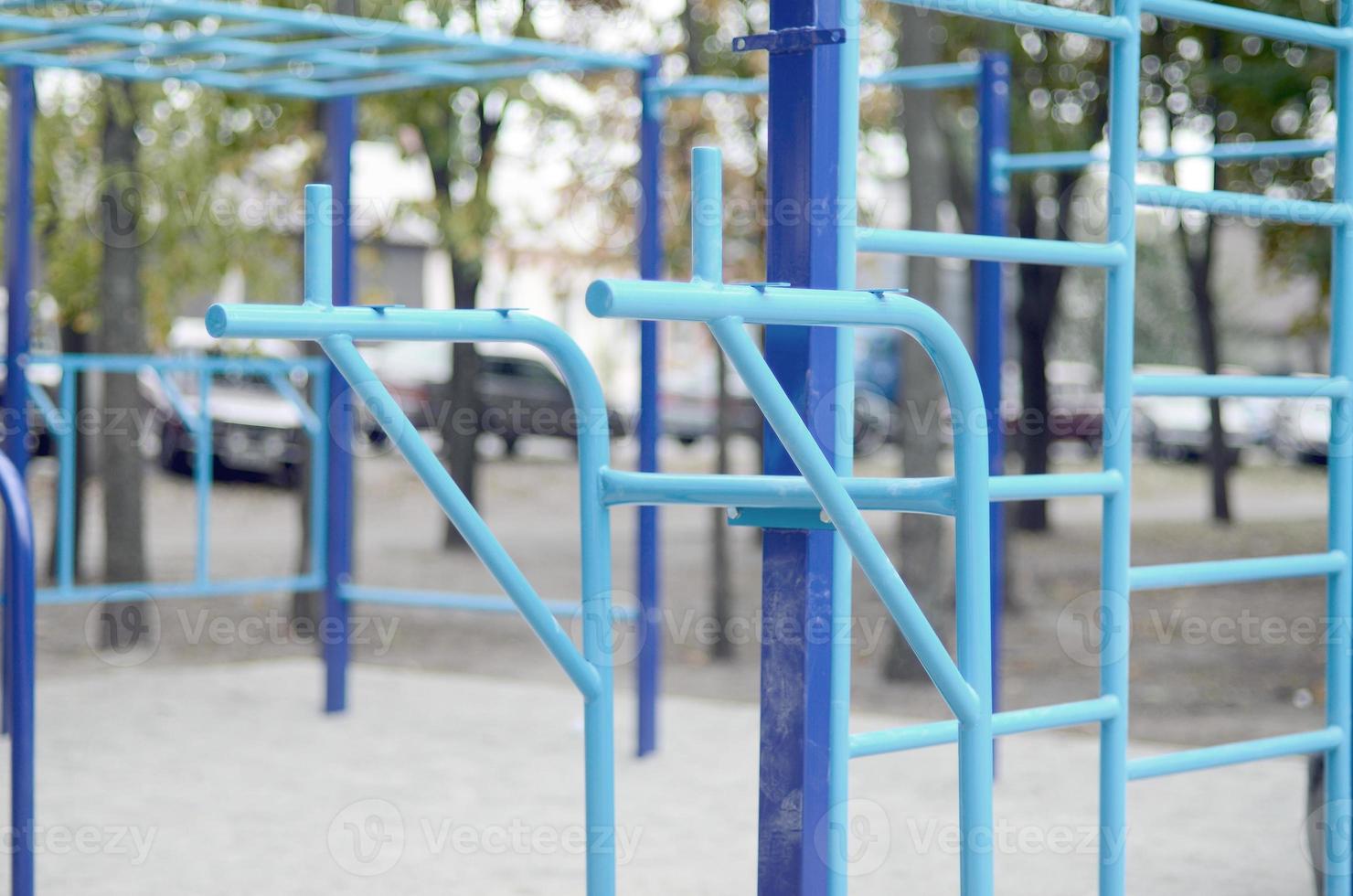 Sports bars in blue on the background of a street sports ground for training in athletics. Outdoor athletic gym equipment. Macro photo with selective focus and extremely blurred background