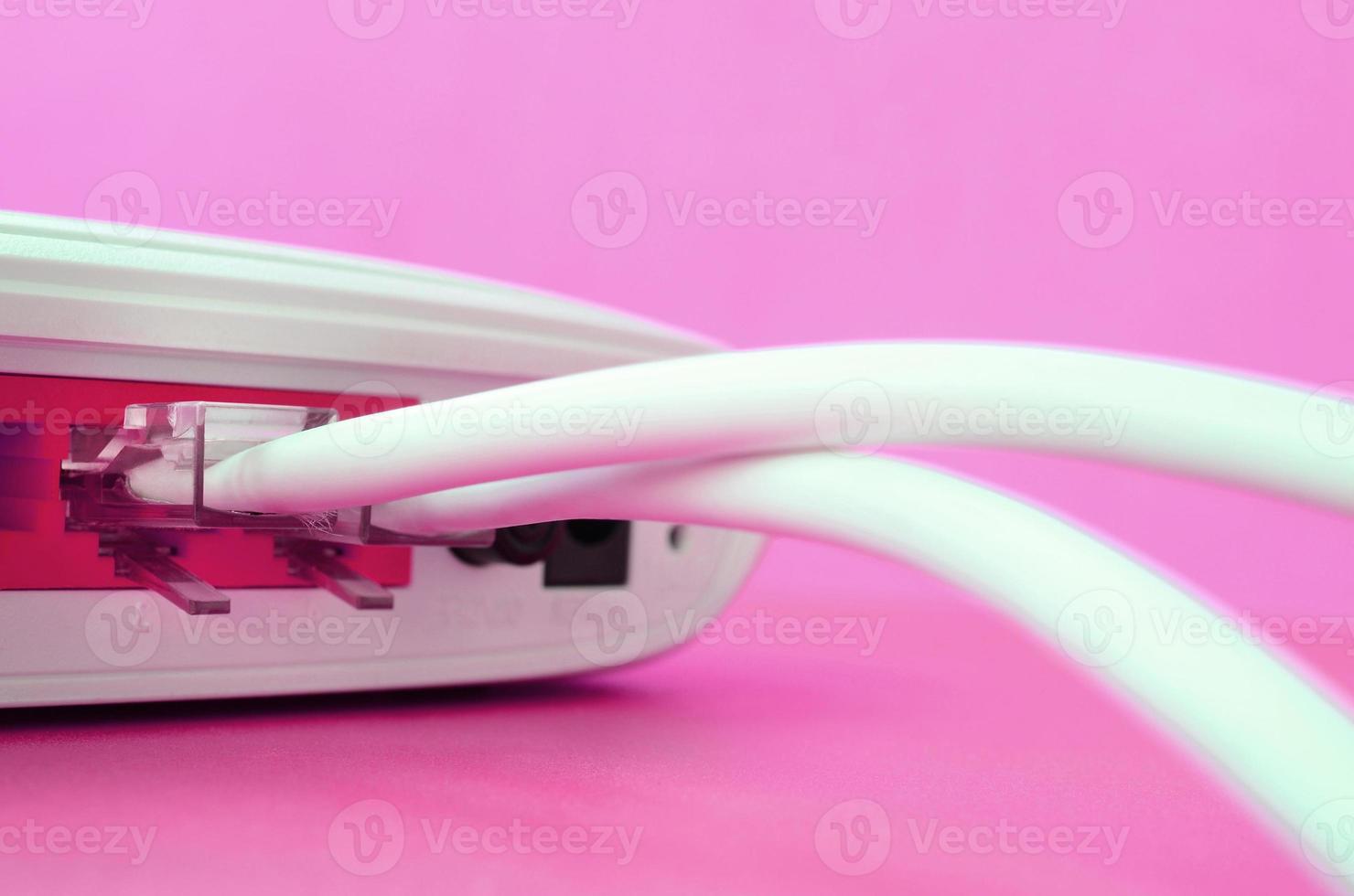 The Internet cable plugs are connected to the Internet router, which lies on a bright pink background. Items required for Internet photo