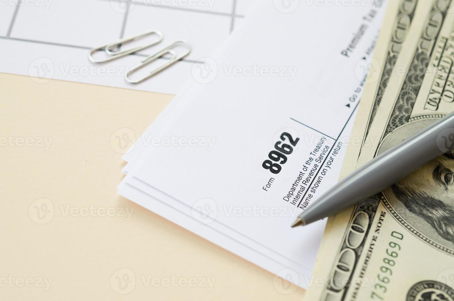 IRS Form 8962 Premium tax cerdit PTC blank lies with pen and many hundred dollar bills on calendar page photo