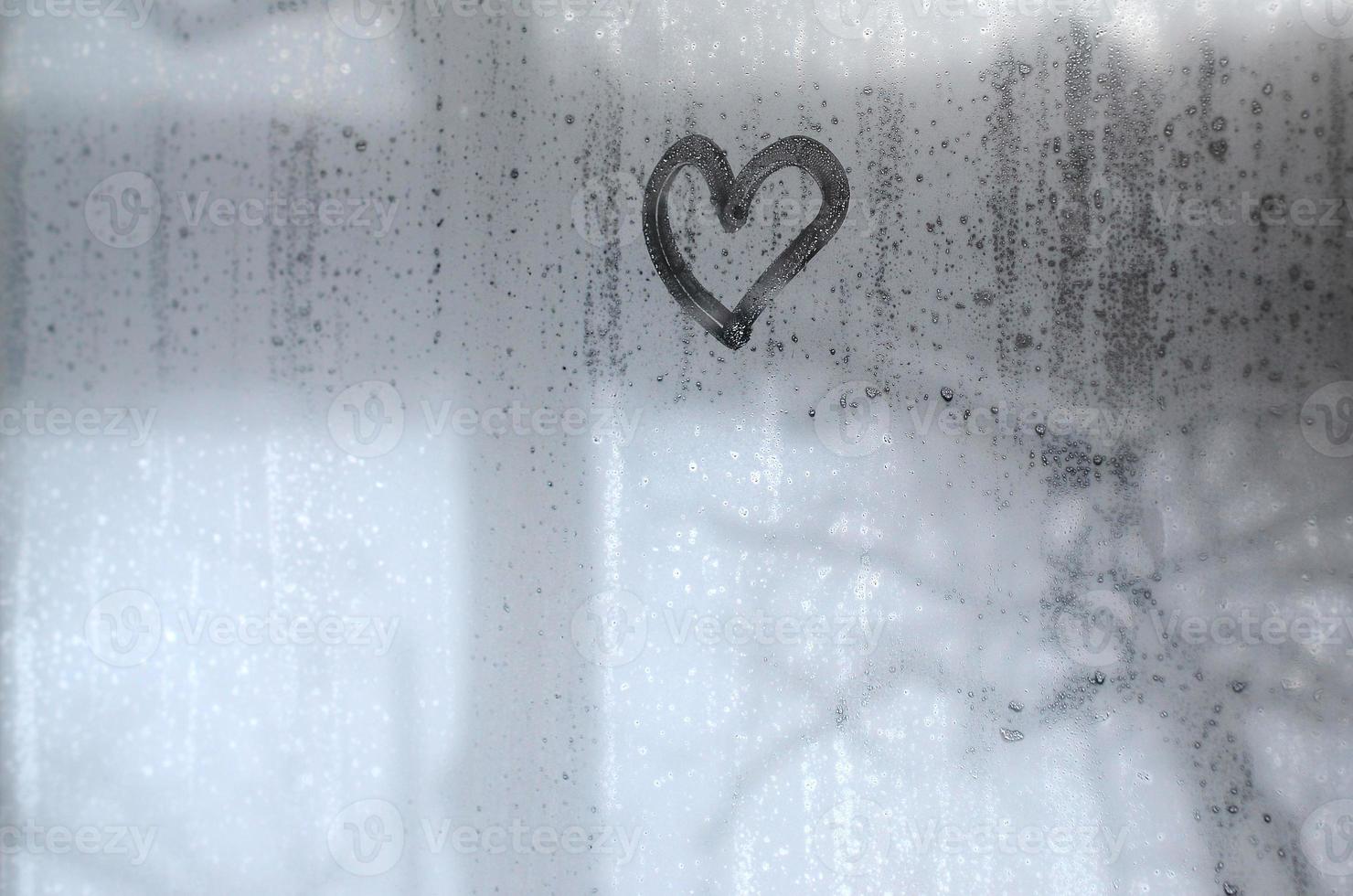 The heart is painted on the misted glass in the winter photo