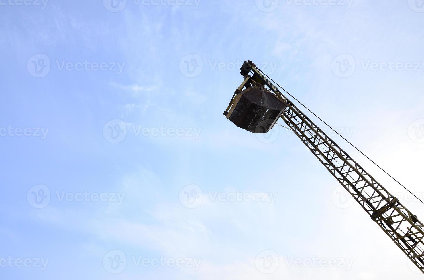 Old yellow mechanical clamshell grab on blue sky background photo