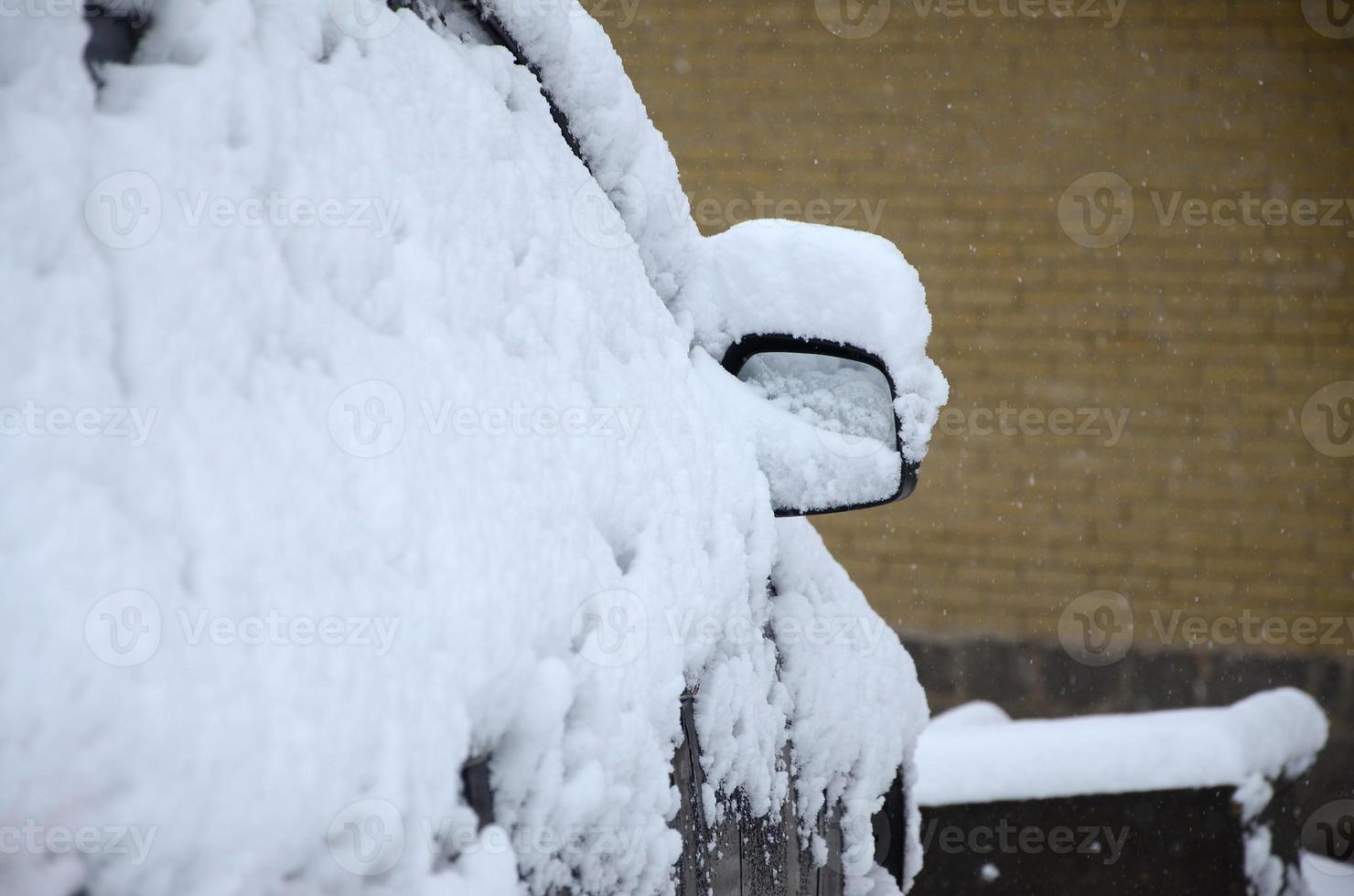 Fragment of the car under a layer of snow after a heavy snowfall. The body of the car is covered with white snow photo
