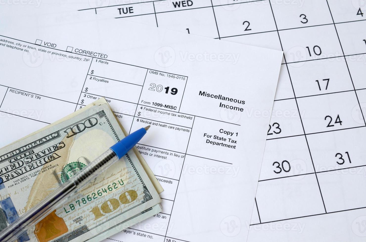 Form 1099-misc Miscellaneous income and blue pen with dollar bills lies on office calendar. Internal revenue service tax form photo