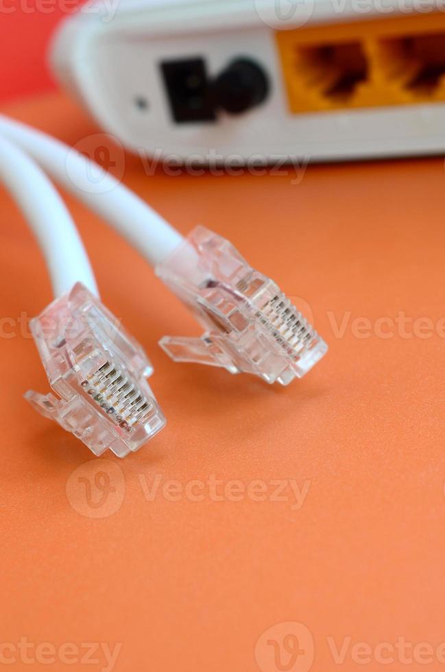 Internet router and Internet cable plugs lie on a bright orange background. Items required for Internet connection photo