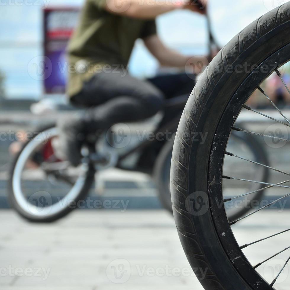 A BMX bike wheel against the backdrop of a blurred street with cycling riders. Extreme Sports Concept photo