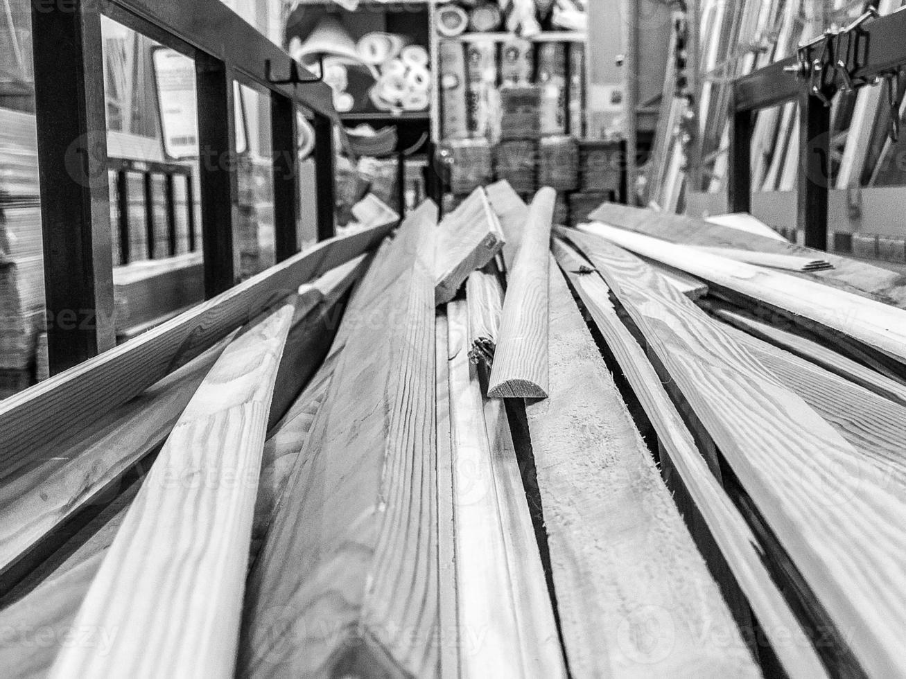 Wooden black and white sawn natural construction boards stick logs with knots on a rack at a sawmill in a store. The background photo