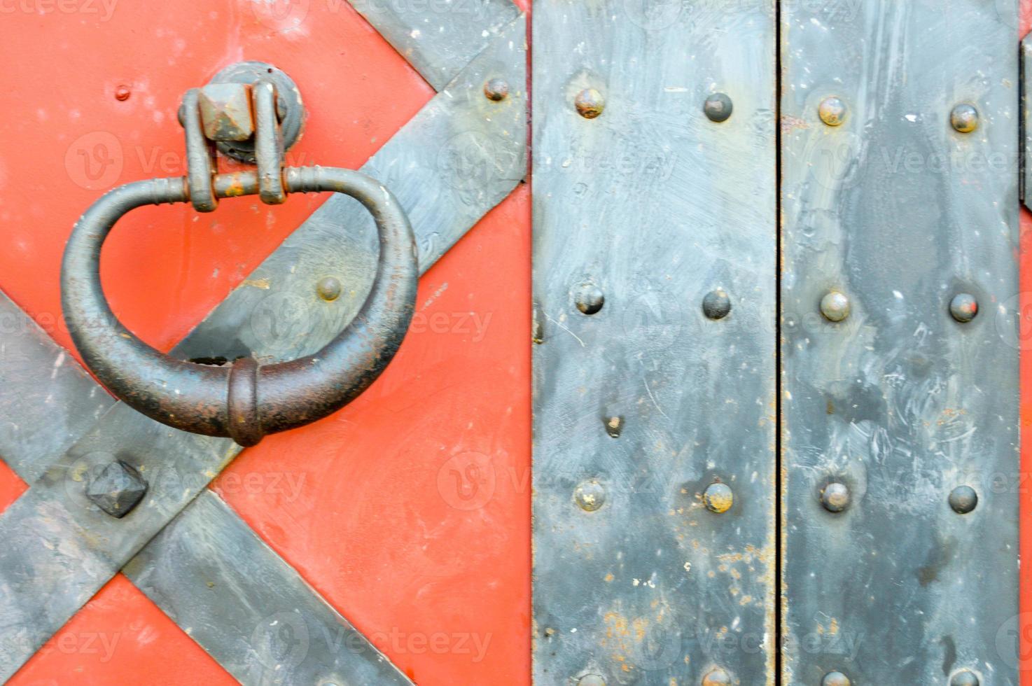 Texture of an old ancient medieval red antique sturdy iron metal door with rivets and nails patterns. The background photo