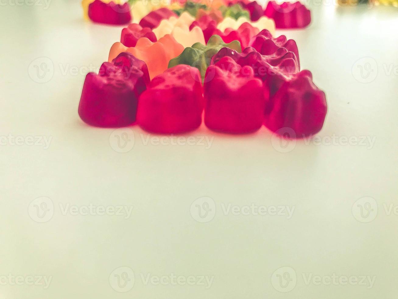 voluminous, bright gelatinous gummy bears. bears lie on a matte background. one row of bears. gelatinous delicious candies. vitamin dessert made from juices and nectars photo