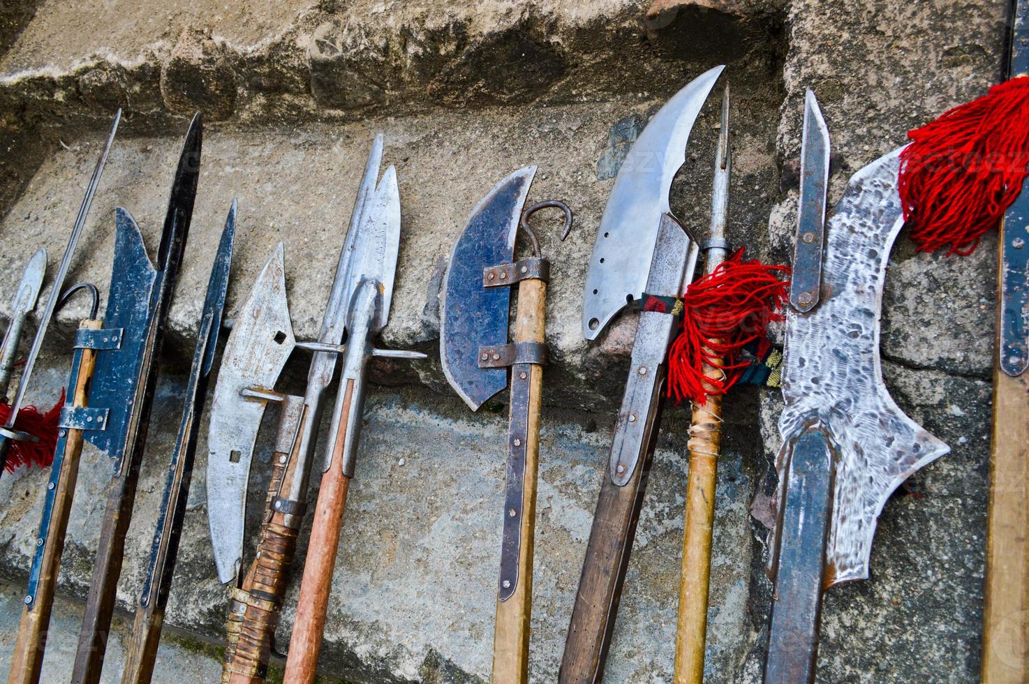 The old ancient medieval cold weapons, axes, olibards, knives, swords with wooden handles lick on the stone steps of the castle photo