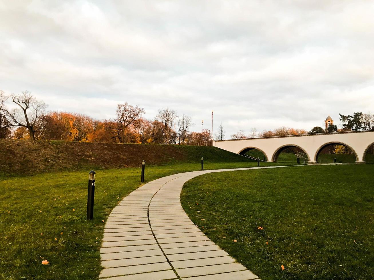 Stone path, a path in the park leading to a pedestrian bridge with arches under it. Landscape park in the fall. photo