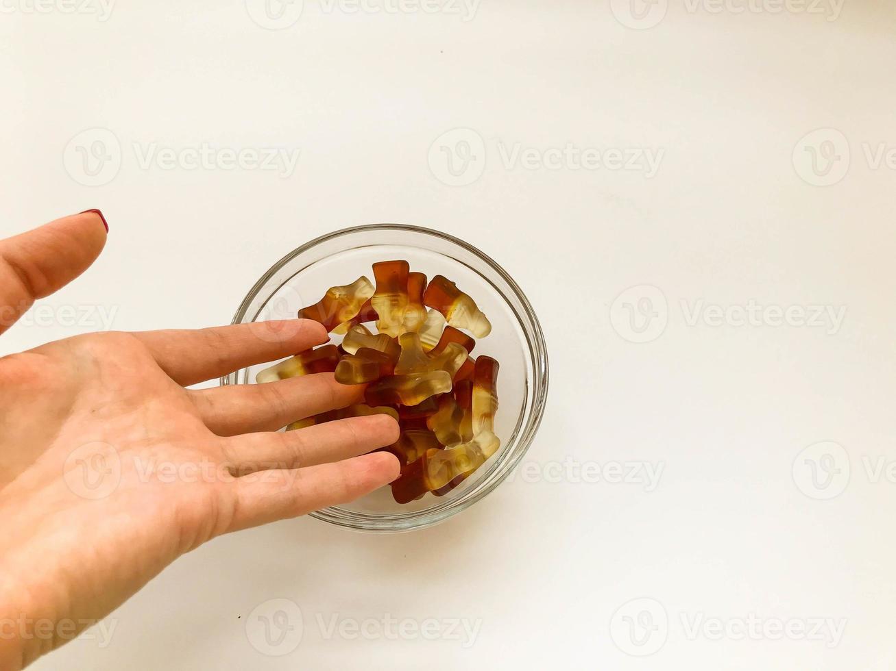 fruit gelatinous sweets. jelly in the form of a bottle is poured from the hand into a round plate. dessert for children and adults. tasty and sweet treat photo