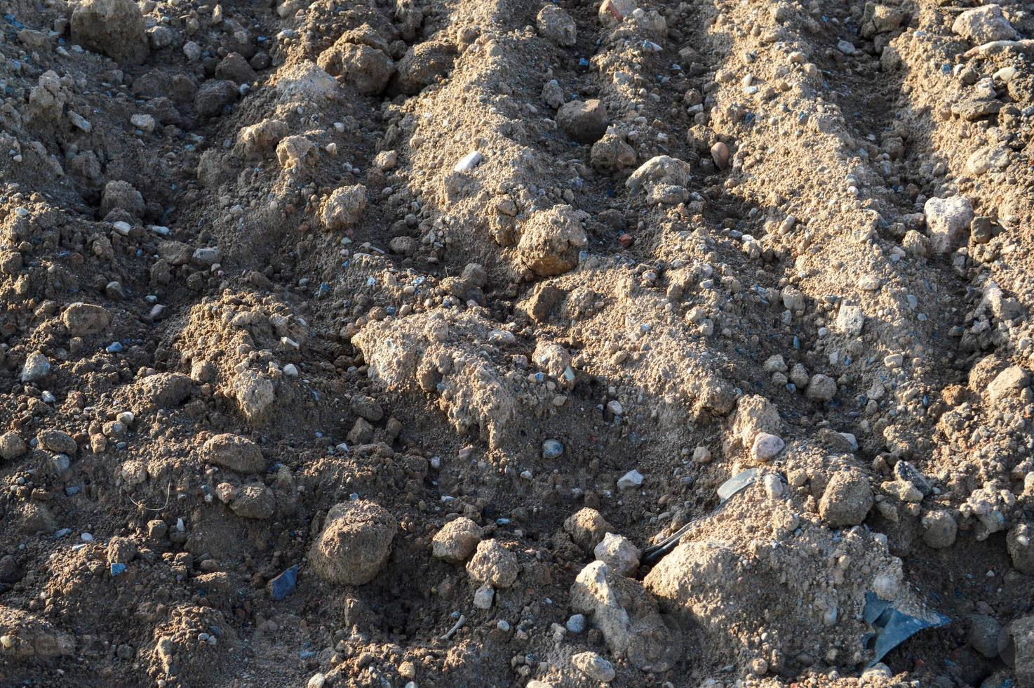 sand lies in the center of city at a  site. construction vehicles are driving on the sand for the construction complex. footprints in the sand from the car are strewn with white small stones photo