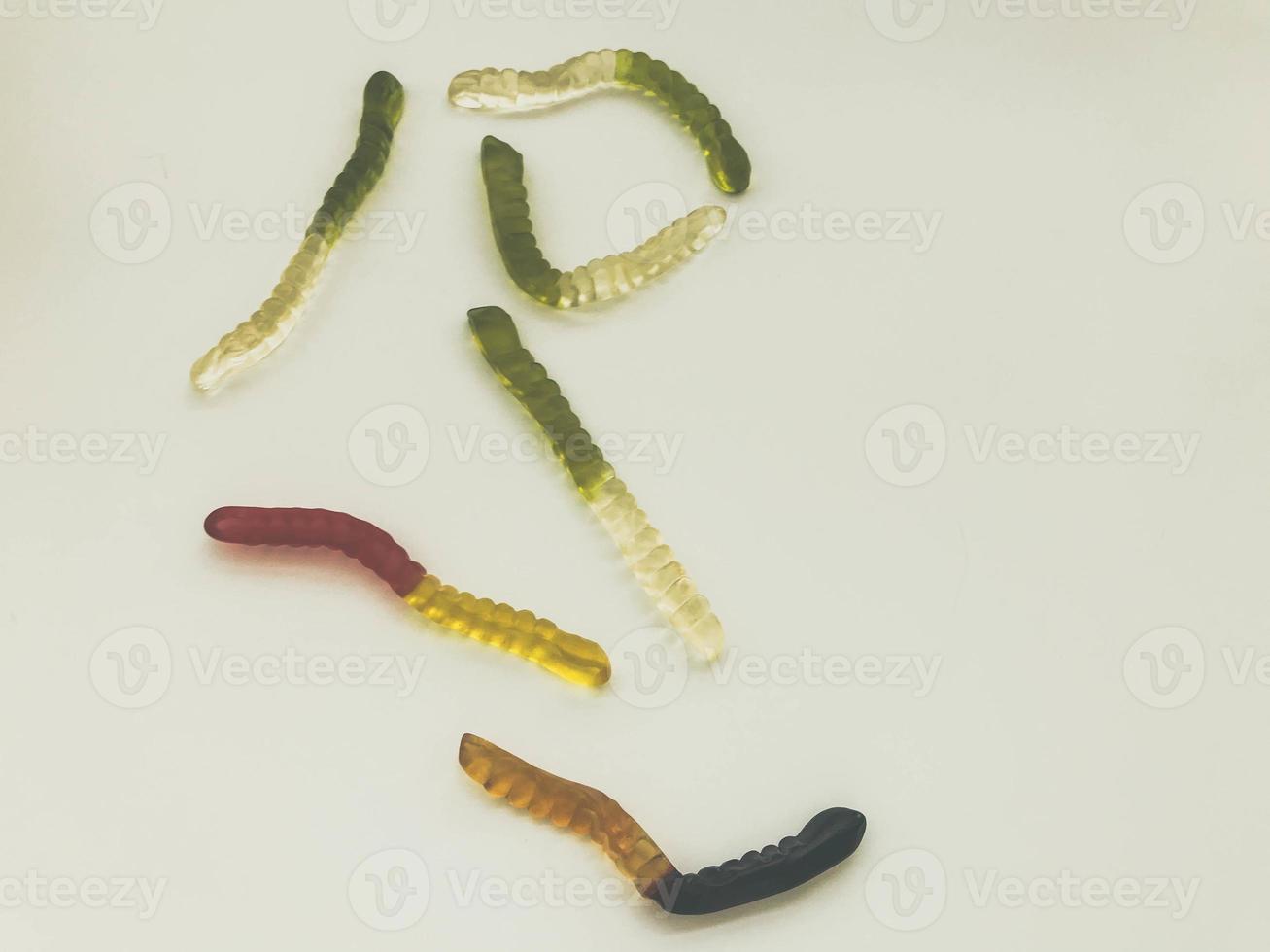 Bright tasty beautiful juicy multi-colored gelatinous gummy sweet candies worms lie on a white background photo