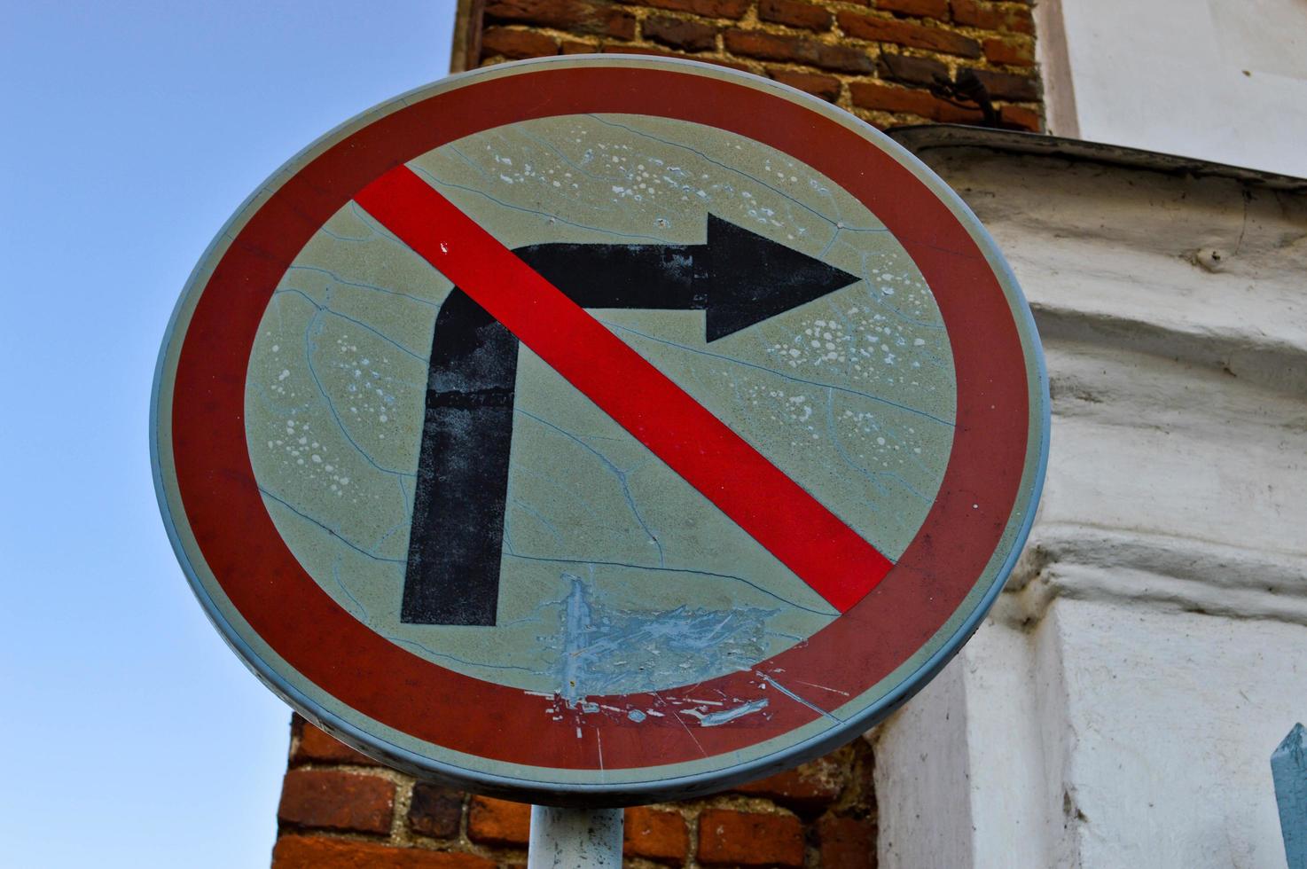 Old shabby cracked round iron road sign prohibiting the right turn is prohibited. The background photo