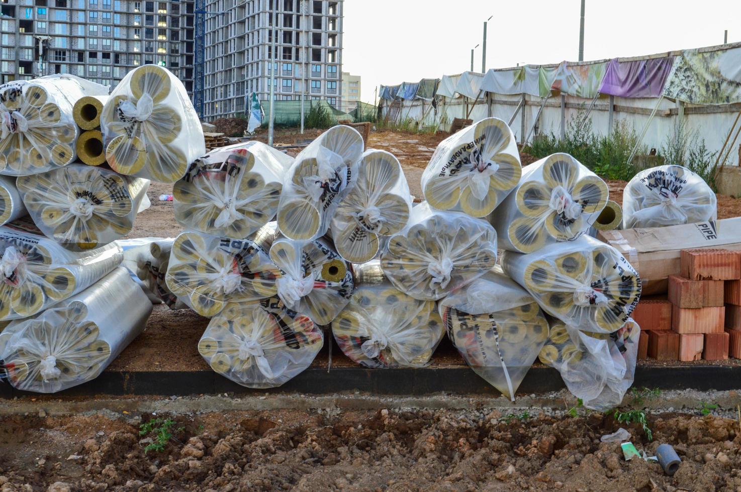 at the construction site the film is folded in spools, in plastic bags. large concrete buildings and bricks stand in the background. film for wrapping building materials and tools photo