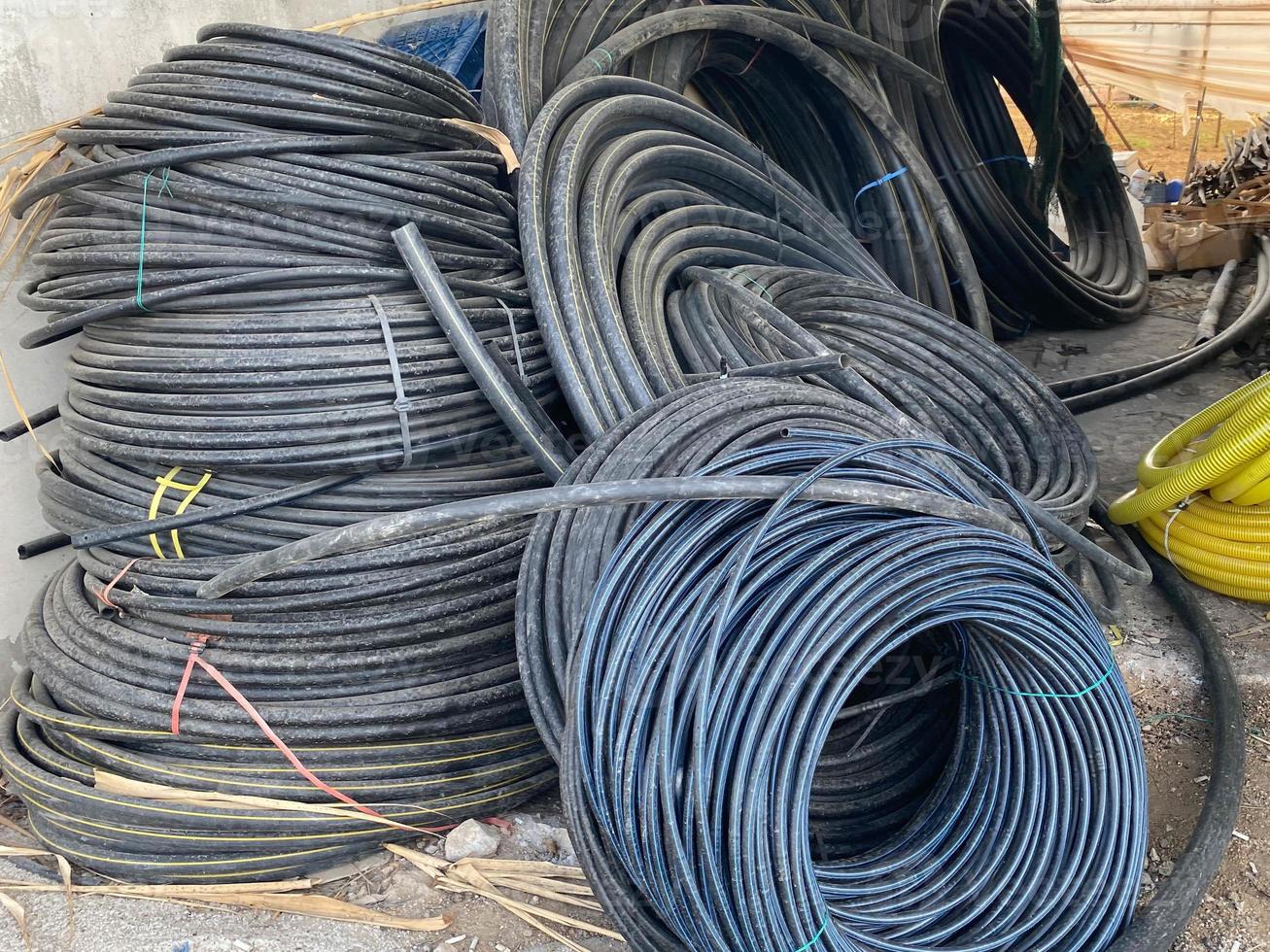 muchas bobinas grandes de cables negros con aislamiento de plástico o cables eléctricos para
