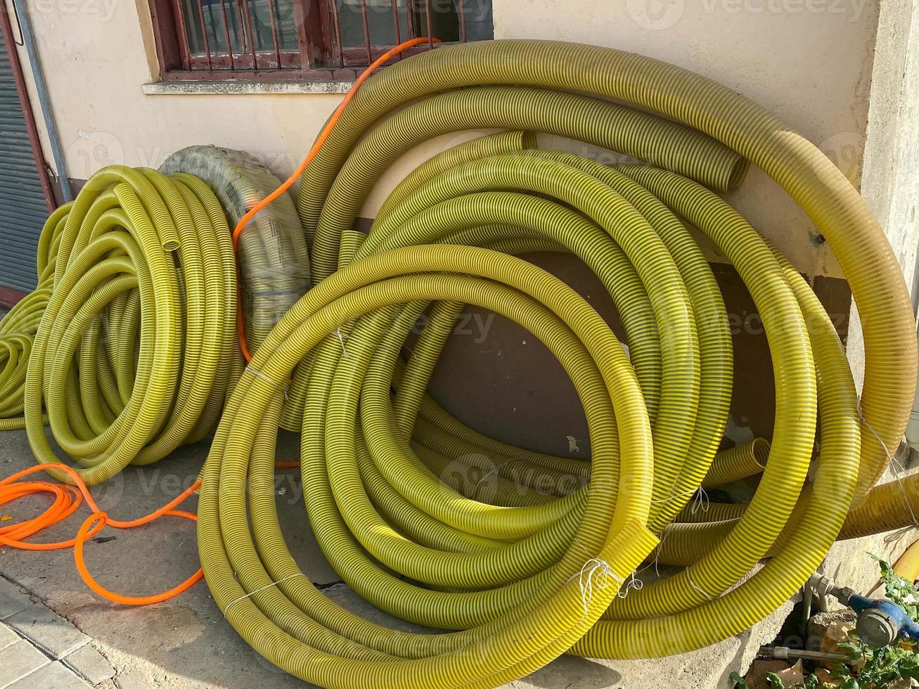 Many large coils of yellow thick plastic hoses of large diameter for pumping liquids in an industrial warehouse photo