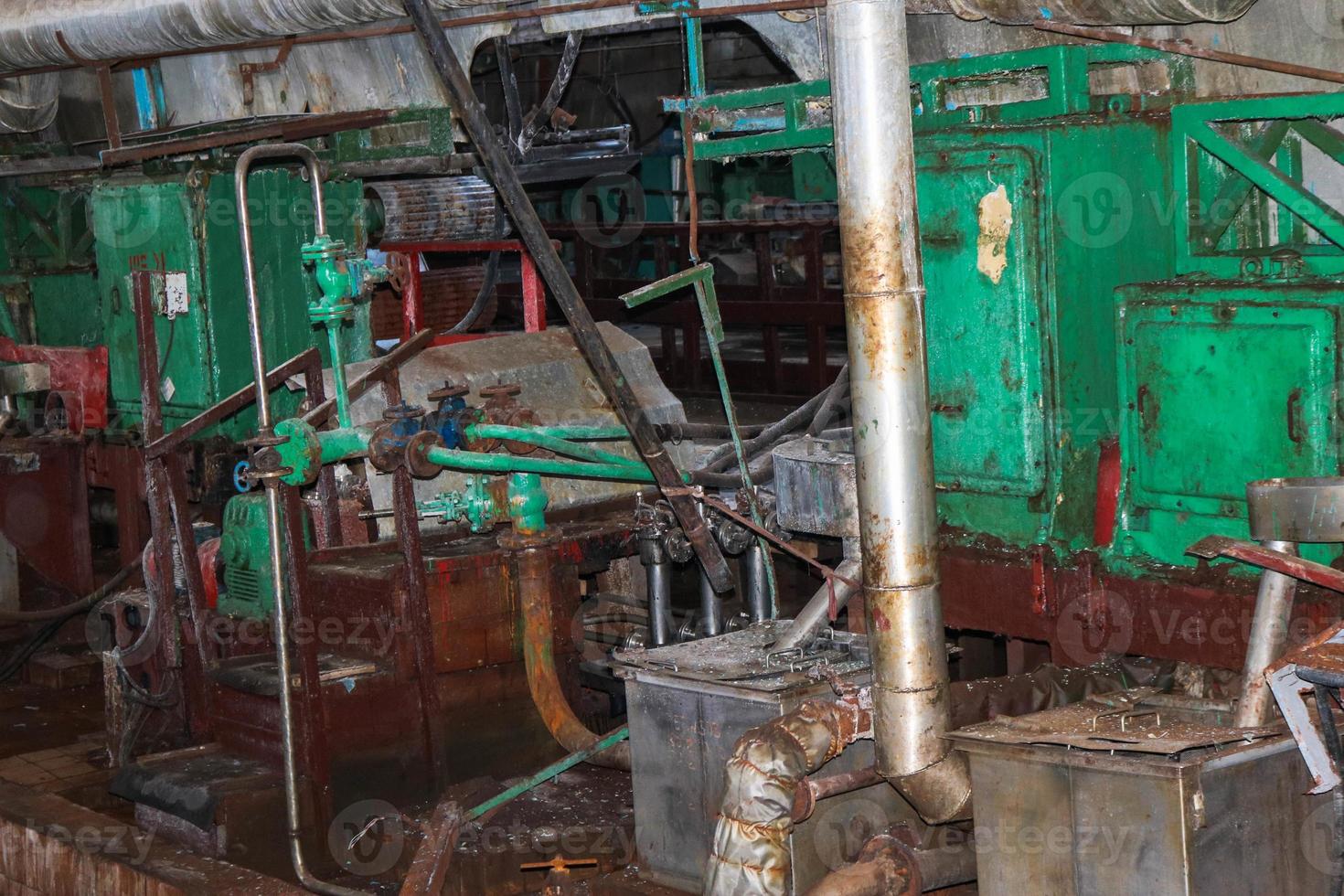 Old rusty closed peeling shop at an abandoned industrial obsolete chemical petrochemical engineering refinery with metal iron pipes of large equipment flanges and hoses pumps photo