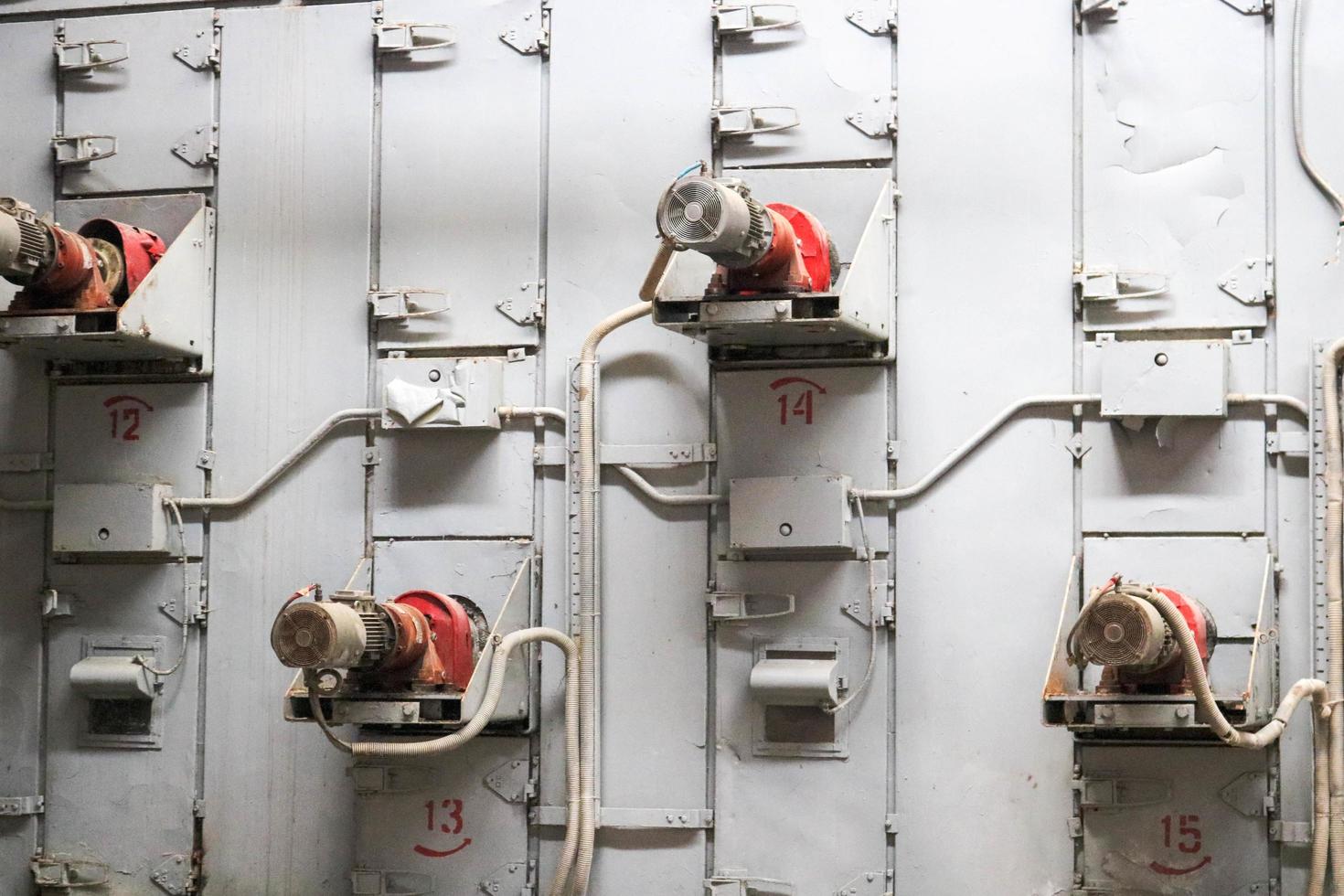 Many industrial metal asynchronous electric motors in the iron gray wall at a machine-building, chemical, petrochemical, and oil refinery plant. The background. Texture photo