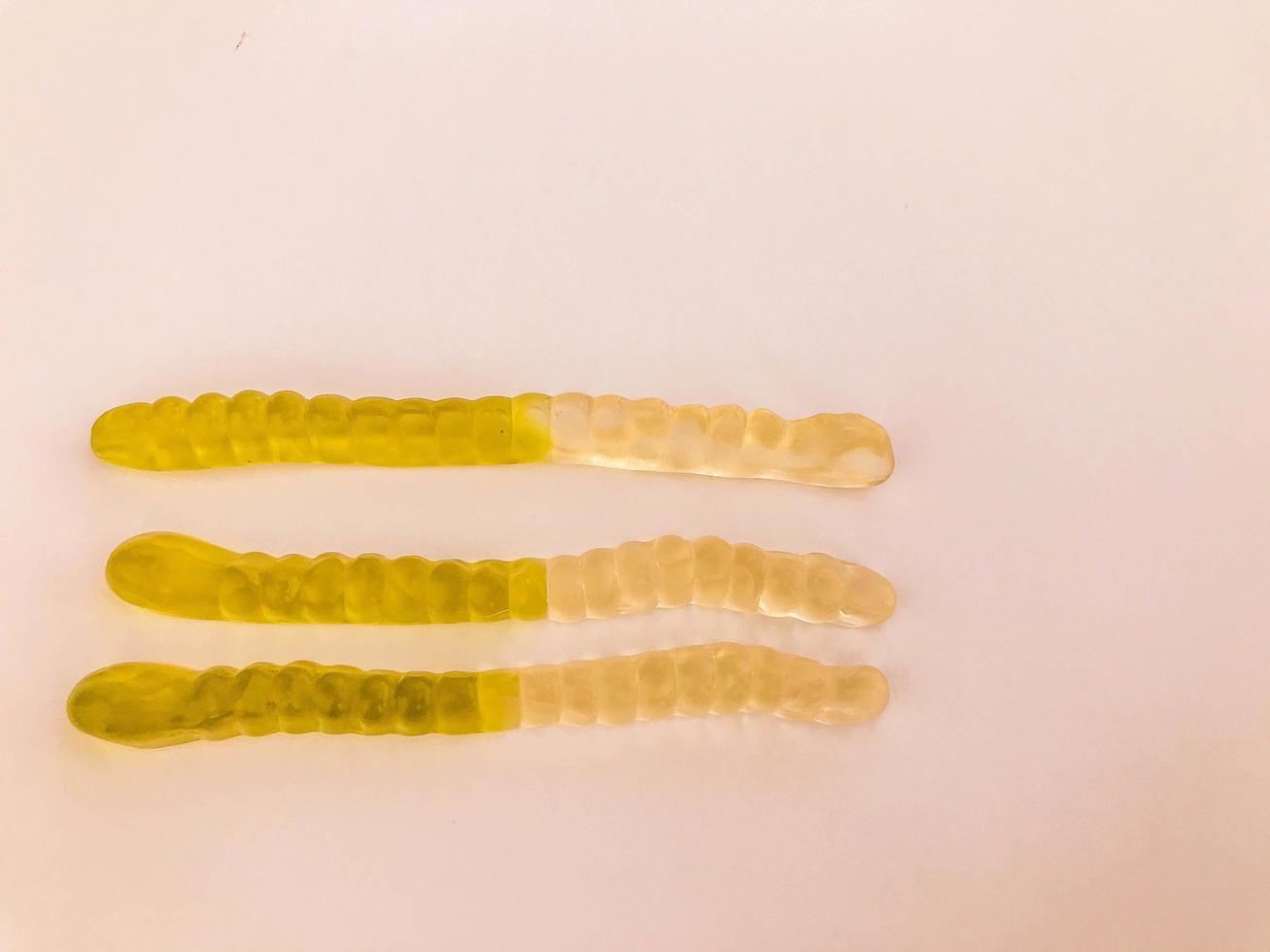 gummy worms lie on a white matte background. bright, mouth-watering gelatinous worms of white-green colors. sweets with volumetric structure, non-uniform shape photo