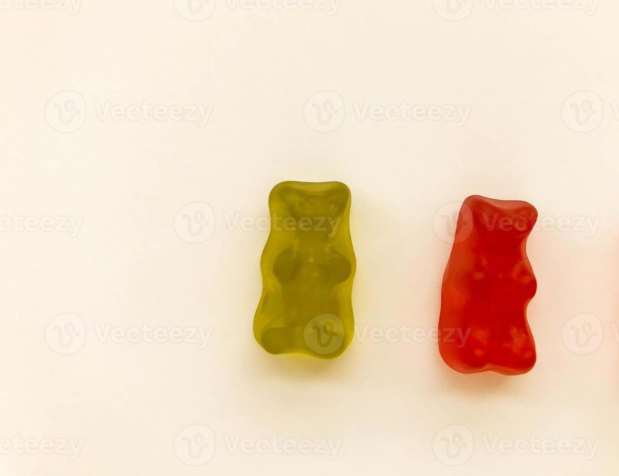 gummy bears of bright colors on a pink matte background. green and red transparent bear. delicious appetizing candies of an unusual shape, high-calorie dessert photo