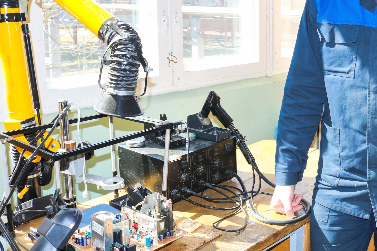 A male working electrician in a robe professionally works on a table for repair in a workshop for remoting electronics and manufacturing parts and spare parts photo