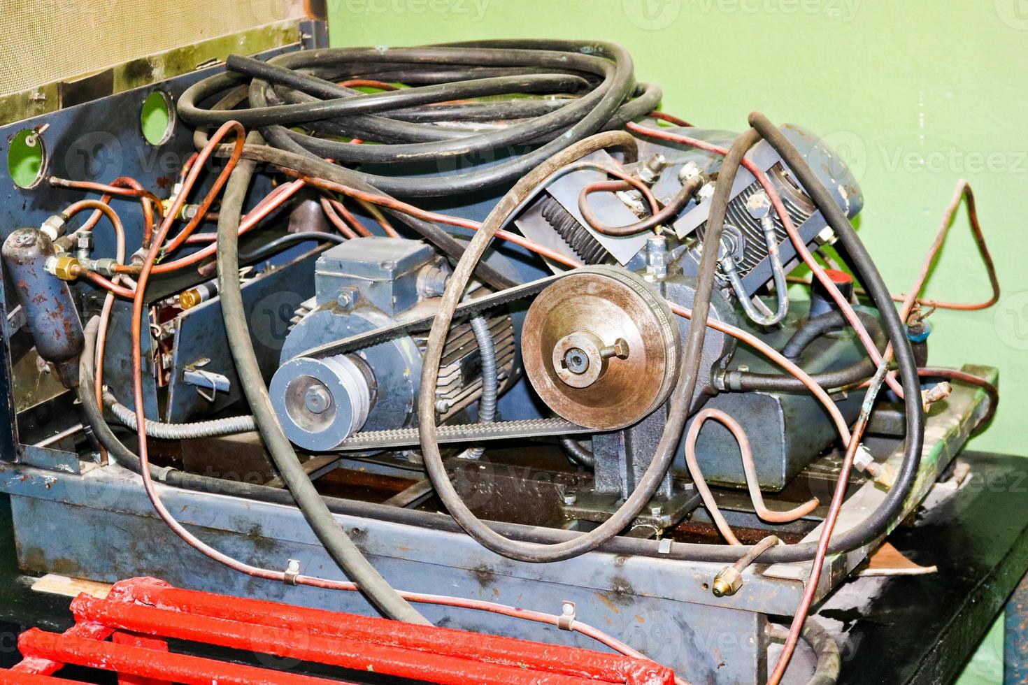 Old asynchronous electric motor with tubes and hoses, belt driven in an industrial plant photo