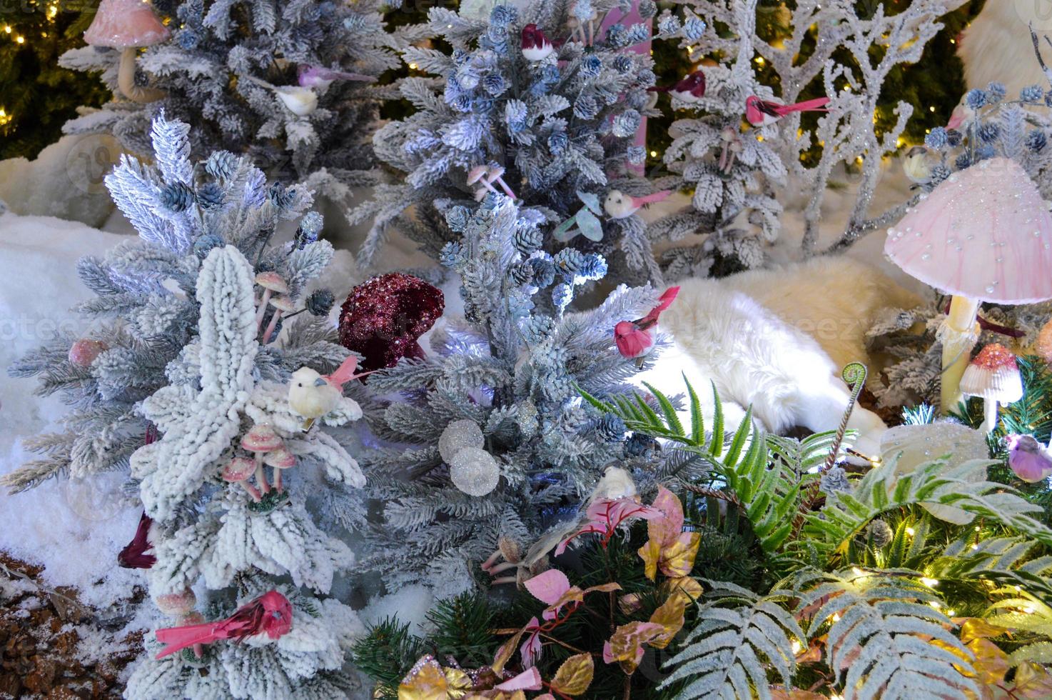 Close-up of a Christmas toy on a snow-covered lively tree in the winter forest on the background of lights photo