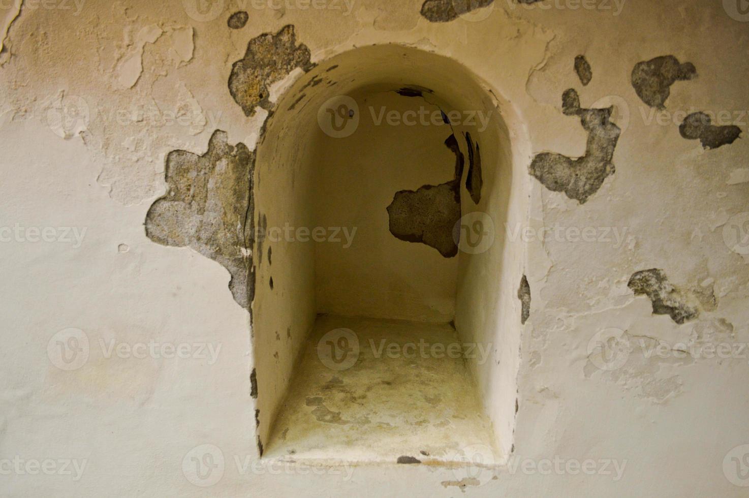 A small narrow recess, a niche with an arch on an old ancient stone white thick concrete wall in an old castle. The background photo