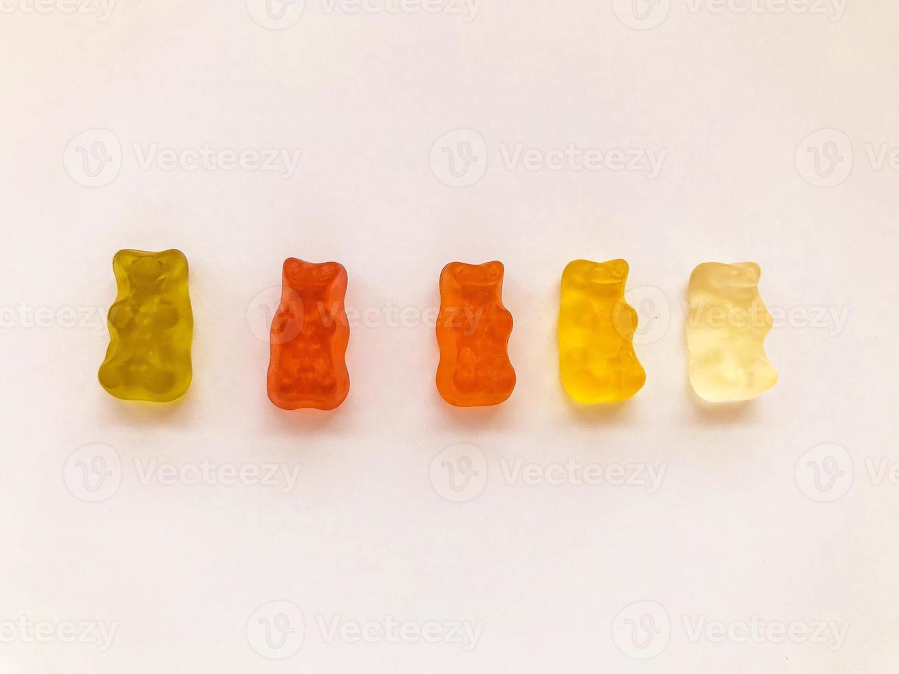gummy bears of bright, different colors on a pink matte background. delicious mouth-watering candies of an unusual shape. high-calorie, cute dessert photo