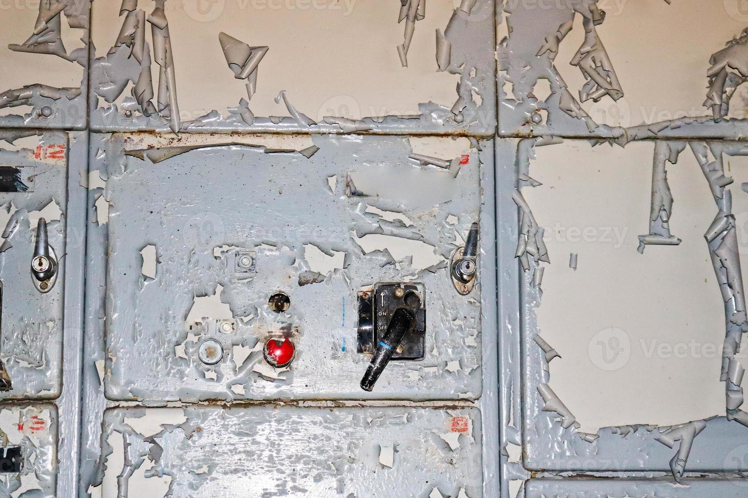 el botón de encendido y el interruptor de palanca para controlar el equipo industrial en la fábrica en el fondo de una pared con pintura agrietada en mal estado foto