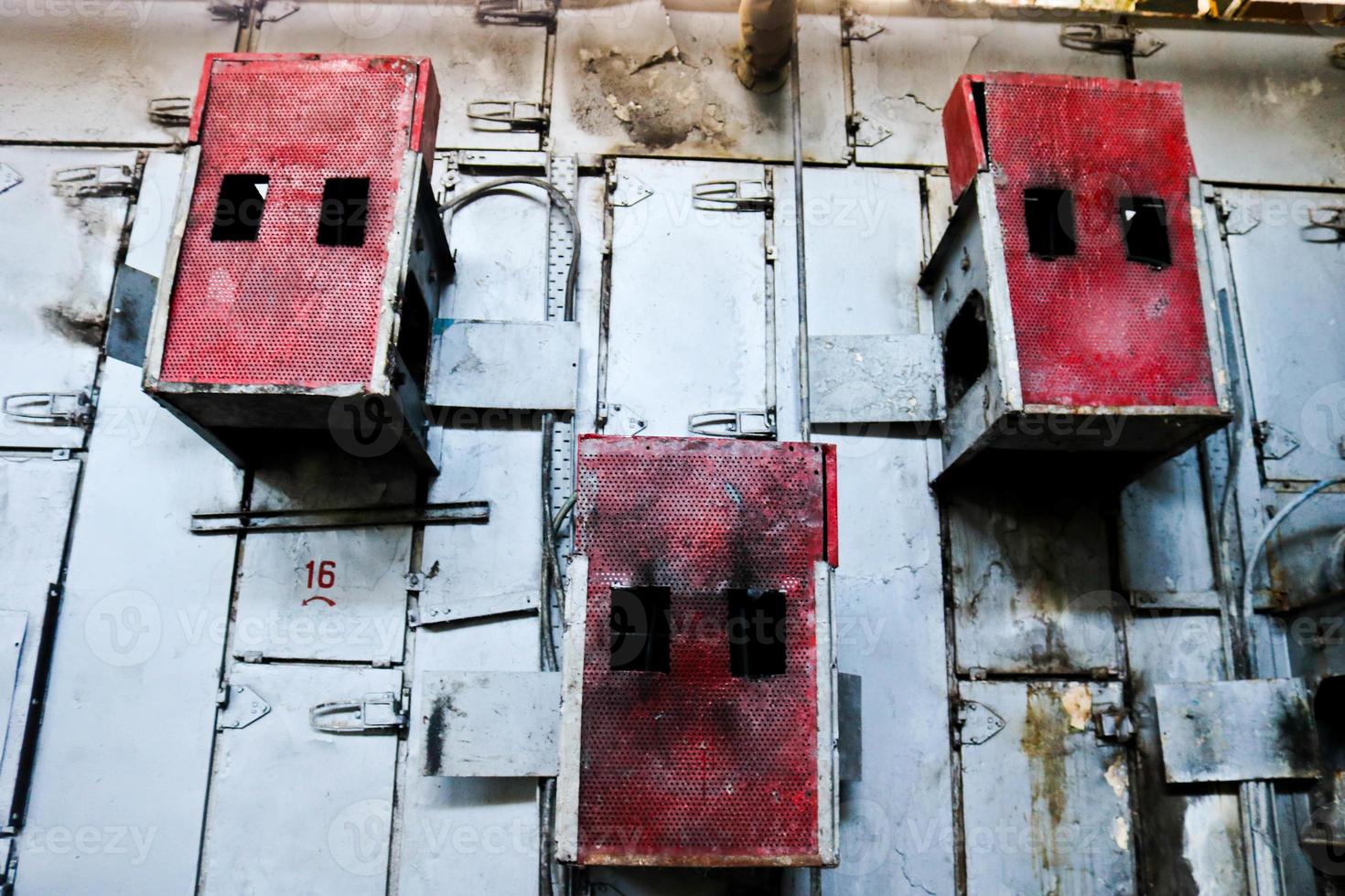 Iron metal red cabinets for perforated electric grid equipment located on a wall at an industrial petrochemical chemical refinery photo