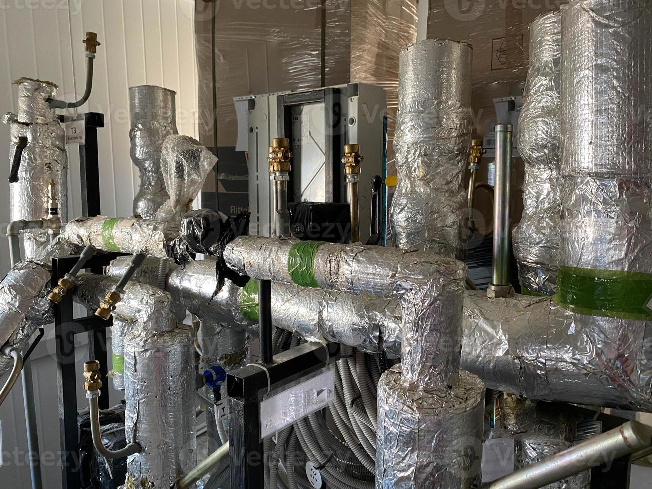 Pipes with tubes and flanges in silver mineral wool thermal insulation to save heat for pumping liquids in refinery petrochemical plant equipment photo