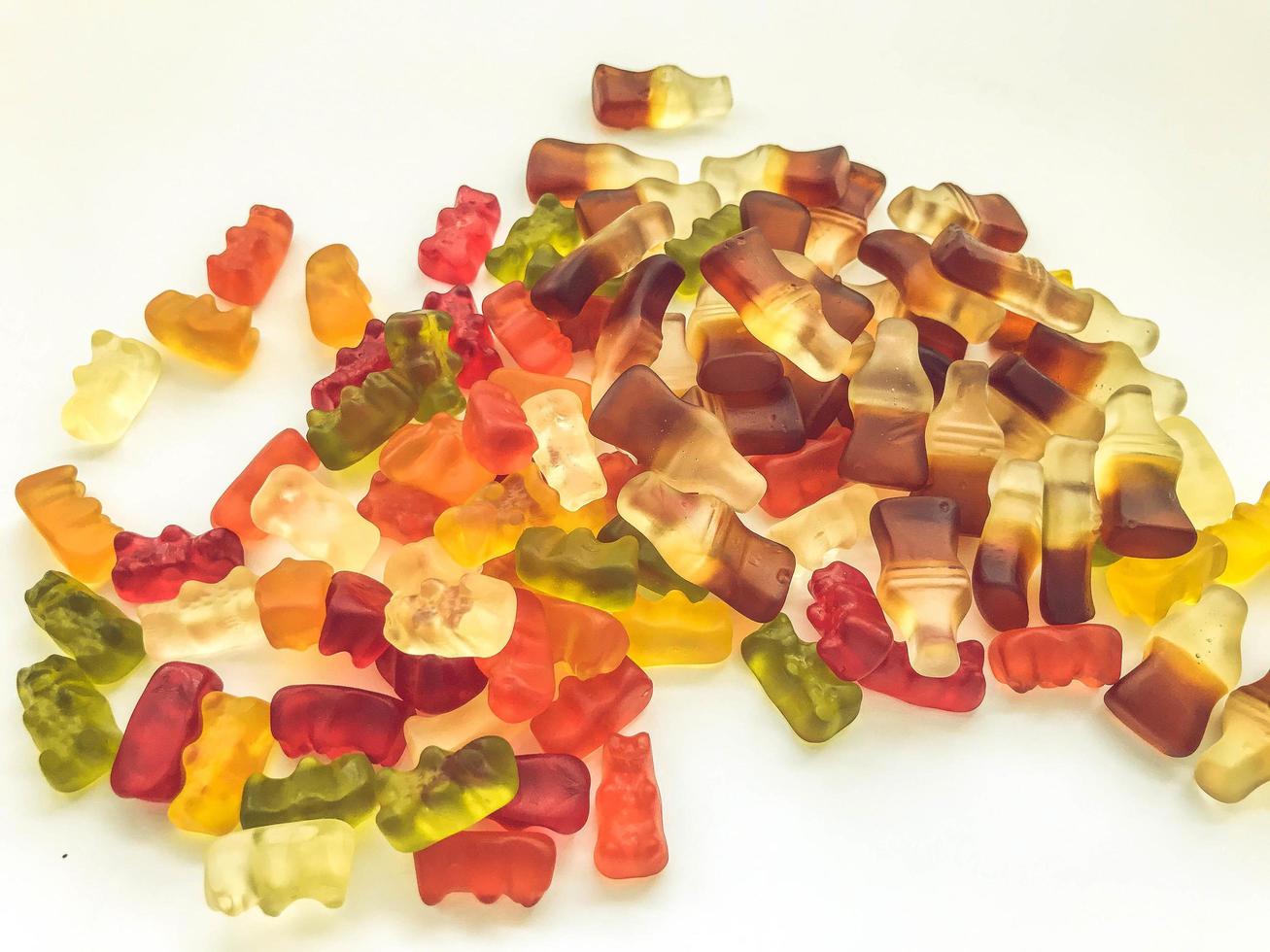 Gomitas brillantes, sabrosas e inusuales hechas de gelatina de varias formas. dulces de colores hechos de frutas. delicioso postre doblado en el fondo foto