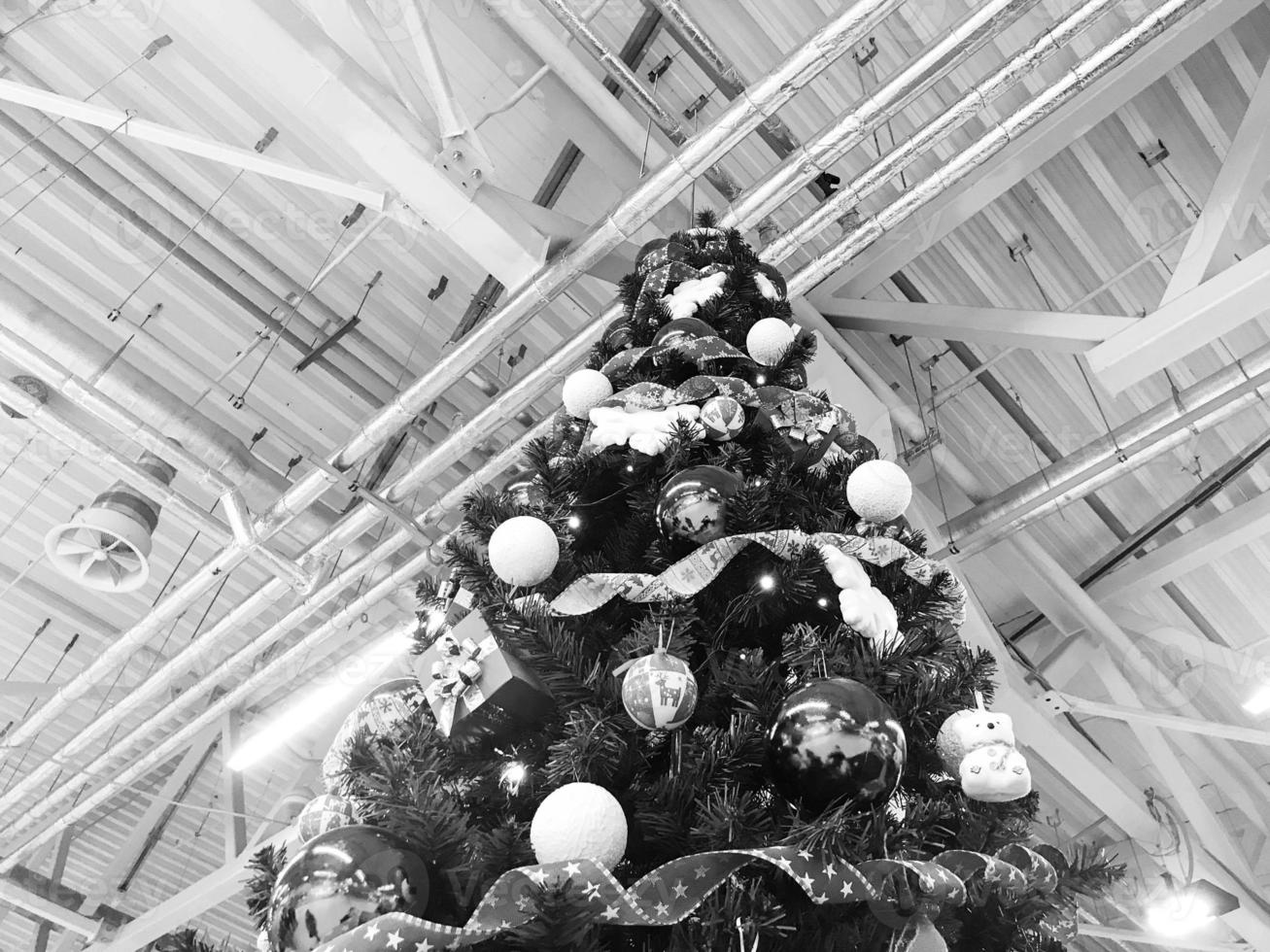 Festive green beautiful elegant Christmas tree with balls for the New Year on the background of the ceiling with metal ventilation pipes in the loft style. Concept Christmas at an industrial plant photo