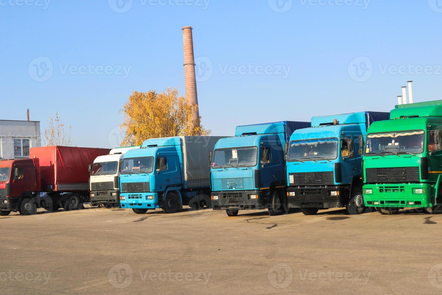 Large heavy cargo trucks with cabs and trailers stand in a row ready for delivery of cargo at the industrial refinery against the background of pipes, transport logistics shop photo