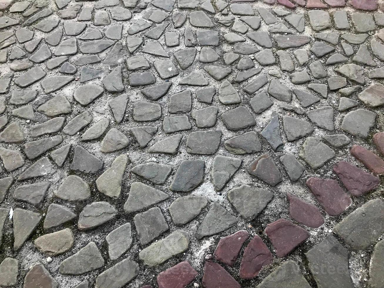 The texture of the stone road, pavement, walls of large gray old medieval round strong stones, cobblestones. The background photo