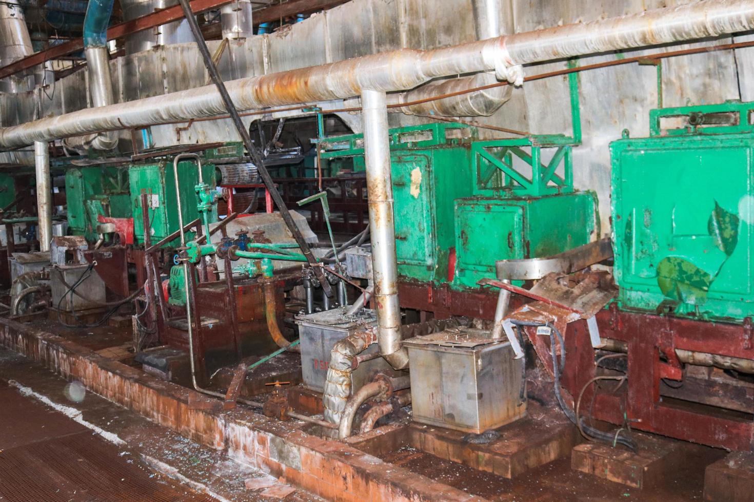 Old rusty closed peeling shop at an abandoned industrial obsolete chemical petrochemical engineering refinery with metal iron pipes of large equipment flanges and hoses pumps photo