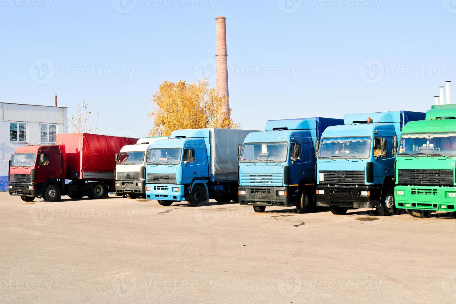 grandes camiones pesados de carga con cabinas y remolques se paran en fila listos para la entrega de carga en la refinería industrial en el contexto de tuberías, tienda de logística de transporte foto