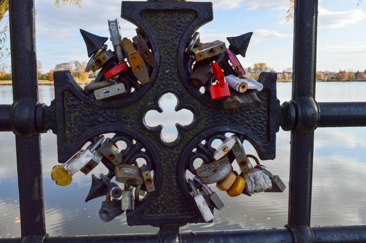 A lot of barn locks hang hitched to the bridge railing. Wedding tradition to hang locks on bridges for eternal love photo