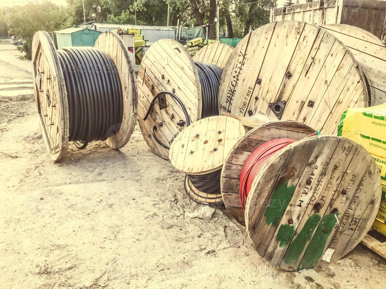 Madejas redondas de madera con cable eléctrico. el cable se enrolla en un carrete grande de madera. sitio de construcción, tendido de cables subterráneos para proporcionar electricidad a la zona foto