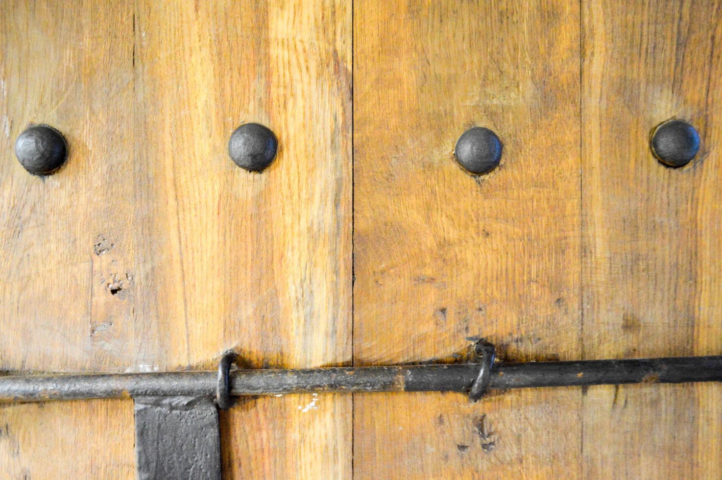 Texture of old ancient medieval antique sturdy wooden natural thick door with rivets and nails patterns and locks made of wooden planks. The background photo