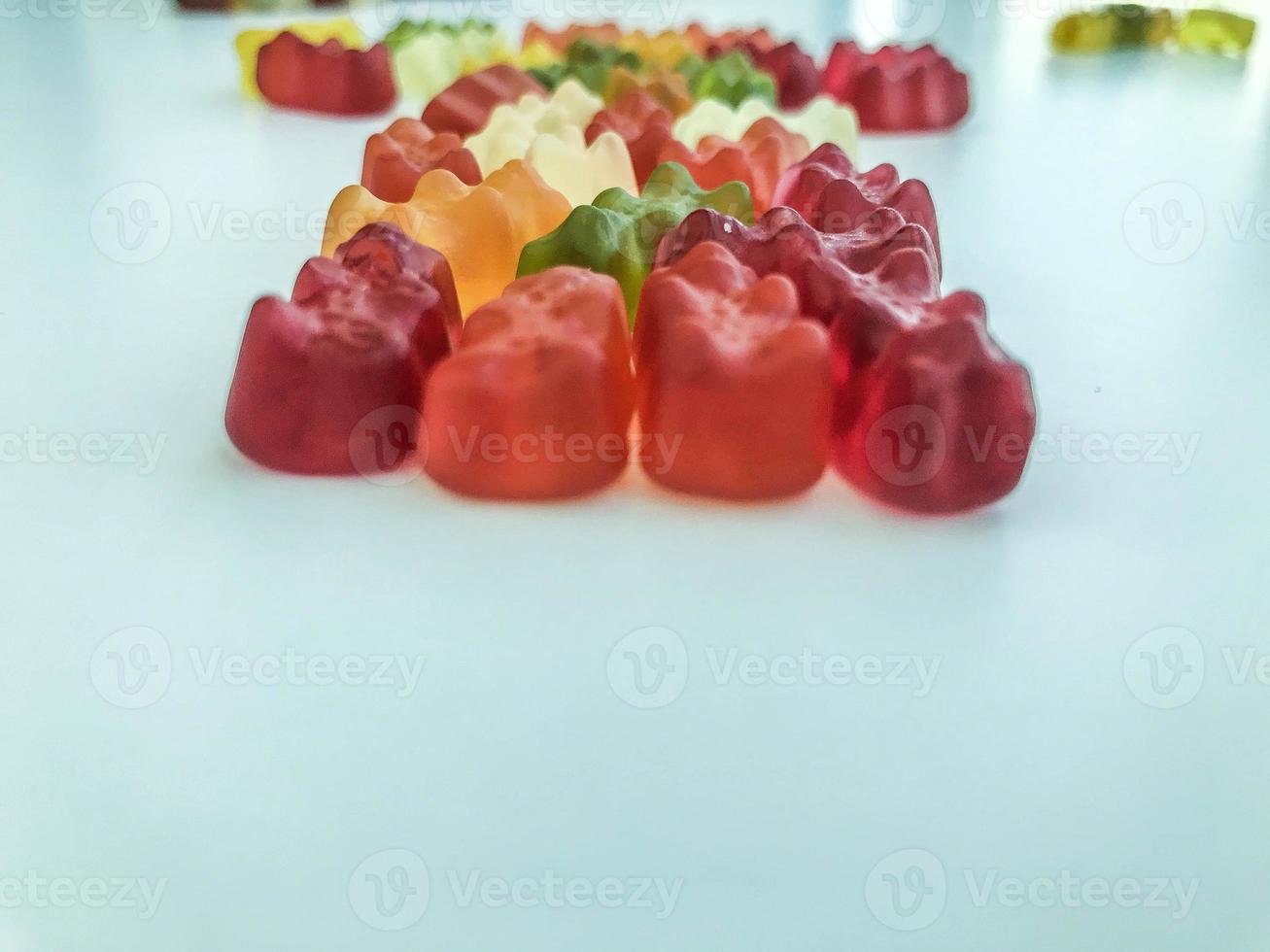 voluminous, bright gelatinous gummy bears. bears lie on a matte background. bears are stacked in one row in the shape of a figure. decorating cakes and desserts photo