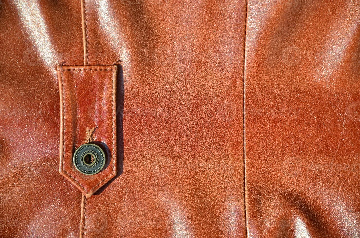 Brown leather texture. Useful as background for any design work. Macro photo of a button on outer clothing made of genuine leather