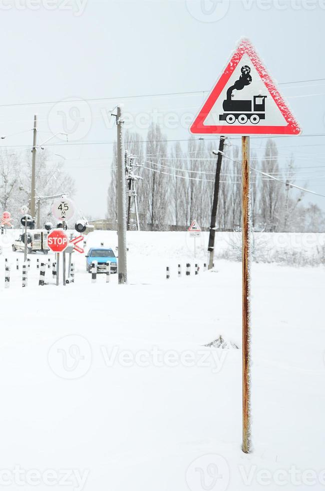 Railway crossing without a barrier with a lot of warning signs in the snowy winter season photo