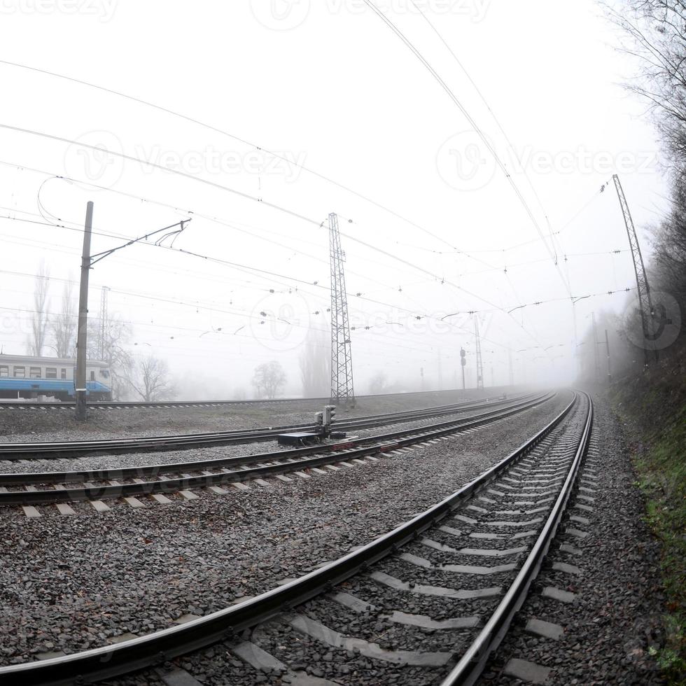 The Ukrainian suburban train rushes along the railway in a misty morning. Fisheye photo with increased distortion