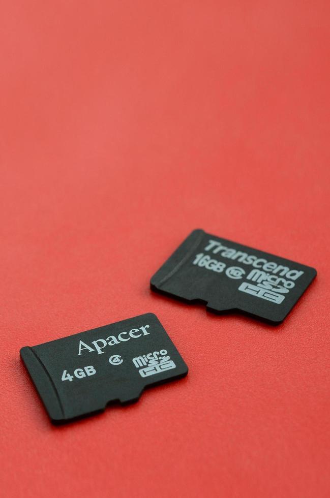 kharkov, ucrania - 29 de diciembre de 2017 dos pequeñas tarjetas de memoria micro sd apacer 4 gb y superan 16 gb se encuentran sobre un fondo rojo. editorial ilustrativa foto