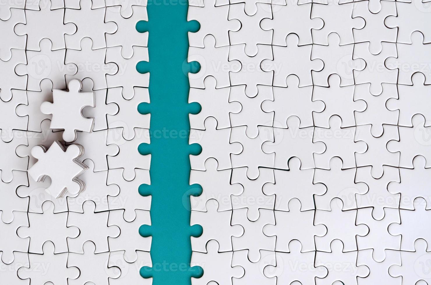 The blue path is laid on the platform of a white folded jigsaw puzzle. The missing elements of the puzzle are stacked nearby. Texture image with space for text photo