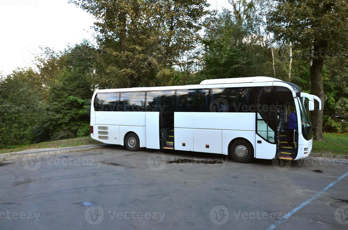 White tourist bus for excursions. The bus is parked in a parking lot near the park photo